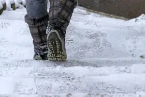 a woman goes down a staircase in winter wearing boots to prevent falls and wounds. Winter wound prevention erie