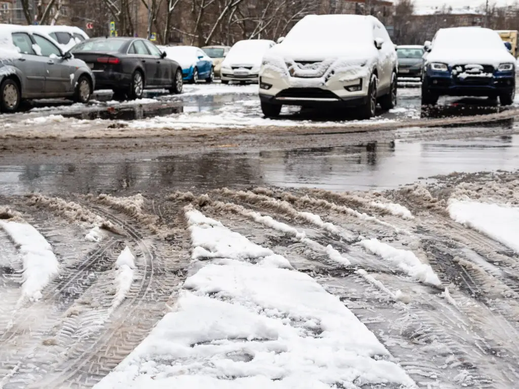 This is a slushy and snowy parking lot with snow covered cars and tire tracks for use in a 2 minute warm up winter fall prevention post