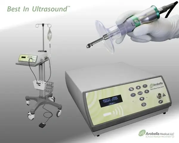 mist ultrasound wound care unit including machine, saline pole, and a gloved hand holding the treatment wand.