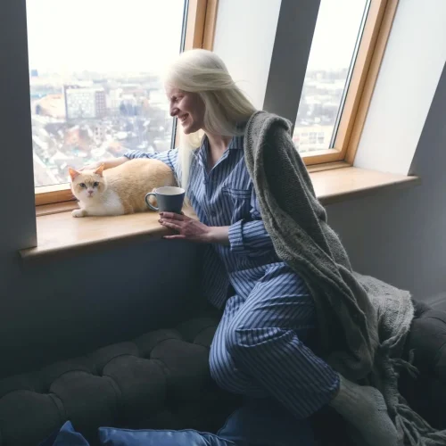 lady and cat looking out the window while seated on the couch to highlight pressure ulcer prevention erie pa winter