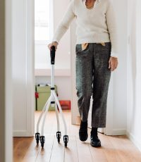 Senior adult walking indoors with a rollator, promoting mobility and independence.
